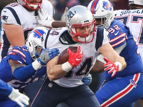 Rex Burkhead of the New England Patriots runs the ball as Jordan Poyer and Adolphus Washington of the Buffalo Bills attempt to tackle him December 3, 2017 at New Era Field in Orchard Park, New York.