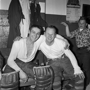 Toronto Maple Leafs goaltenders Terry Sawchuk (left) and Johnny Bower share a happy moment in the team's Maple Leaf Gardens dressing room during the mid-1960s. In the background is Bower's young son, John Jr. MANDATORY CREDIT: COURTESY JOHNNY BOWER COLLECTION