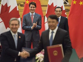 Canadian Prime Minister Justin Trudeau, rear left, and Chinese Premier Li Keqiang, rear right, applaud during a signing ceremony at the Great Hall of the People in Beijing Monday, Dec. 4, 2017.