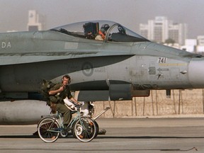 A Canadian CF-18 pilot prepares to take off, as a member of the ground crew pedals his bicycle past the jet in Qatar, January 20, 1991 during the Gulf War. The Trudeau government is adding a new requirement to how it picks the winners of major military contracts by assessing a company's overall impact on the Canadian economy.