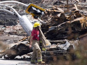 A firefighter walks by rubble on the train crash site in Lac-Megantic, Que., Sunday, July 14, 2013. The three men charged in the Lac-Megantic rail disaster that killed 47 people will not be testifying at their trial.