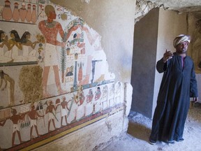An Egyptian guard stands next to a funeral mural inside a newly discovered tomb on Luxor's West Bank known as "KAMPP 161" during an announcement for the Egyptian Ministry of antiquities about new discoveries in Luxor, Egypt, Saturday, Dec. 9, 2017.