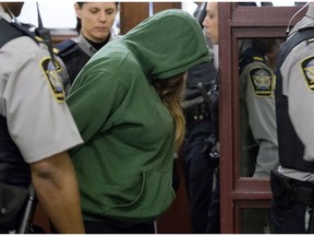 Melissa Merritt is escorted at provincial court in Halifax on Wednesday, Jan. 29, 2014. Merritt, 33, and her common-law spouse Christopher Fattore, 36, face first-degree murder charges in the death of her ex-husband and his mother in a Toronto-area home.