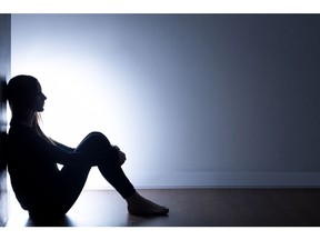 Teenager with depression sitting alone in dark room.
