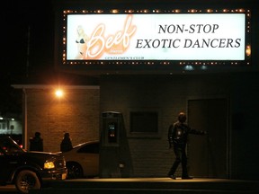 A man enters The Beef Baron Gentleman's Club light up the night in London, Ontario on Thursday Dec. 7, 2017 . The city's sex workers and local advocates are slamming politicians over a bylaw that bans touching in London strip clubs.