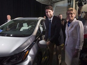Prime Minister Justin Trudeau, left, and Ontario Premier Kathleen Wynne pose as they plug in a 2017 Chevrolet Volt electric vehicle at the General Motors plant in Oshawa, Ont., on Friday, June 10, 2016. THE CANADIAN PRESS/Chris Young