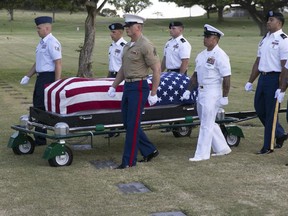 In this July 27, 2015 file photo, military pallbearers escort the exhumed remains of unidentified crew members of the USS Oklahoma killed in the 1941 bombing of Pearl Harbor that were disinterred from a gravesite at the National Memorial Cemetery of the Pacific in Honolulu.