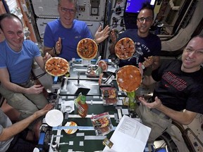 In this Nov. 18, 2017 photo provided by NASA, from left, American Mark Vande Hei, Russian Sergei Ryazanskiy, Italian Paolo Nespoli, American Joe Acaba and American Randy Bresnik display the results of their made-from-scratch pizza pies at the International Space Station.