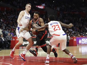 Toronto Raptors' Norman Powell, center, is defended by Los Angeles Clippers' Sam Dekker, left, and Lou Williams during the second half of an NBA basketball game Monday, Dec. 11, 2017, in Los Angeles. The Clippers won 96-91. (AP Photo/Jae C. Hong)