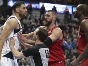 Referee Scott Twardoski (52) and Toronto Raptors centre Jonas Valanciunas hold back Dallas Mavericks center Salah Mejri, left, from going at Raptors forward Serge Ibaka (9) during the second half of an NBA basketball game in Dallas, Tuesday, Dec. 26, 2017. The Mavericks won 98-93. (AP Photo/LM Otero)