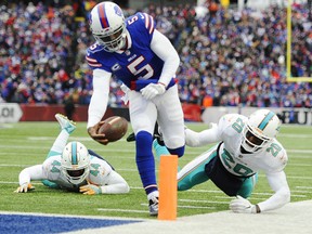 Bills quarterback Tyrod Taylor (5) rushes past Dolphins' Stephone Anthony (44) and Reshad Jones (20) for a touchdown during first half NFL action in Orchard Park, N.Y., on Sunday, Dec. 17, 2017.