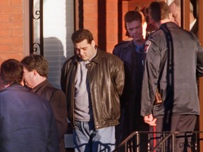Angelo Musitano, centre, is led from home by police yesterday after being charged in the murder of mob boss Johnny Papalia.