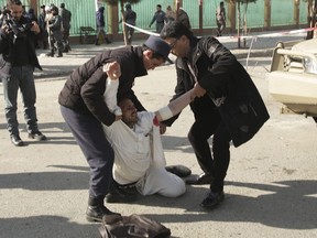 A wounded man is assisted at the site of an explosion in downtown Kabul, Afghanistan, Saturday, Jan. 27, 2018. The Interior Ministry says a suicide car bomb attack in Kabul leaves dozens wounded.