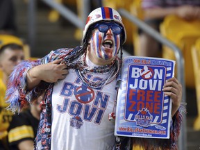A Buffalo Bills fan displays a shirt and a sign in protest of Jon Bon Jovi's interest in the Buffalo Bills. (The Associated Press/File Photo)