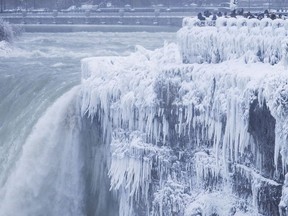 Visitors take photographs at the brink of the Horseshoe Falls in Niagara Falls, Ont., as cold weather continues through much of the province, Tuesday, January 2, 2018.