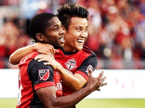 Toronto FC's midfielder Armando Cooper, left, celebrates his assist on a goal by teammate Drew Moor, not shown, with teammate Tsubasa Endoh, right, who also assisted, during first half MLS soccer action against the New England Revolution, in Toronto on Friday, June 23, 2017. CANADIAN PRESS/Nathan Denette