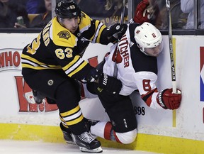 Boston Bruins left wing Brad Marchand checks New Jersey Devils defenceman Will Butcher into the boards during the second period of an NHL hockey game Tuesday, Jan. 23, 2018, in Boston. (AP Photo/Charles Krupa)