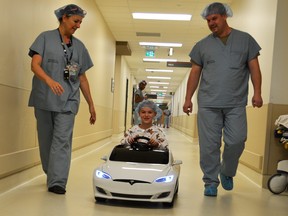 Seven year old, Lucas Skewes, drives himself to the operating room with help from his dad, Aaron and Alexandra Christofides, child life program specialist