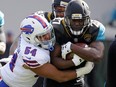 Jaguars running back Leonard Fournette, right, is stopped by Bills defensive end Eddie Yarbrough (54) after a short gain in the first half of an NFL wild-card playoff game, Sunday, Jan. 7, 2018, in Jacksonville, Fla.