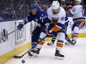 Maple Leafs forward Leo Komarov checks New York Islanders forward Anders Lee along the boards in Toronto on Thursday February 1, 2018. (Jack Boland/Toronto Sun)