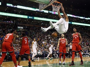 Boston Celtics' Al Horford hangs from the rim after dunking as Toronto Raptors' Fred VanVleet (23) and Serge Ibaka (9) look on during the fourth quarter of an NBA basketball game in Boston, Sunday, Nov. 12, 2017. (AP Photo/Winslow Townson