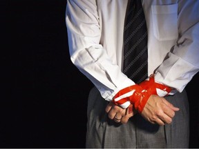 Stock photo of hands being tied with red tape.