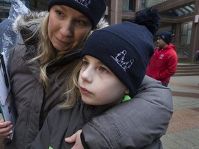 Shona Smith hugs her 10-year-old son at a protest outside Toronto Police headquarters on Monday. (STAN BEHAL, Toronto Sun)