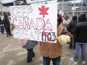 A man hides his face while promoting his anti-Motion 103 sign outside of City Hall in Calgary, Alta., on Saturday, March 4, 2017. Two opposing demonstrations were occurring simultaneously just metres from each other, one supporting Motion 103, which would deem Islamophobia a hate crime, and the other opposing it, saying it would hurt freedom of speech. Lyle Aspinall/Postmedia Network