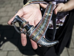 Sukhvinder Kaur Vinning, Executive Director, World Sikh Organization of Canada holds a kirpan outside Provincial Court in Surrey, British Columbia, Wednesday April 10, 2013.