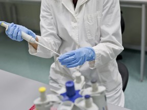 A lab associate in blue gloves performing a DNA test.