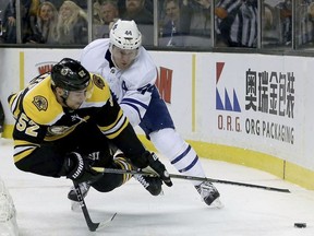 Toronto Maple Leafs defenseman Morgan Rielly (44) trips Boston Bruins center Sean Kuraly (52) who was making a play for the puck behind the net during the second period of an NHL hockey game, Saturday, Feb. 3, 2018, in Boston.