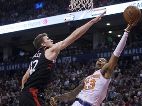 New York Knicks Trey Burke (right) shoots on Toronto Raptors Jakob Poeltl (left) during second half NBA basketball action in Toronto on Thursday, February 8, 2018. THE CANADIAN PRESS