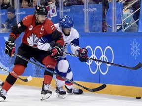 Canada forward Chris Kelly (11) and South Korea forward Kisung Kim (11) vie for control of the puck during first period men's hockey action at the 2018 Olympic Winter Games in Pyeongchang, South Korea, on Sunday, Feb. 18, 2018.