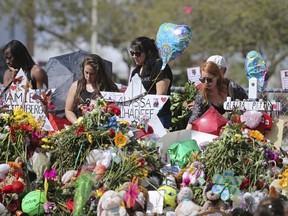 Mourners bring flowers as they pay tribute at a memorial for the victims of the shooting at Marjory Stoneman Douglas High School on Sunday, Feb. 25, 2018, in Parkland, Fla.