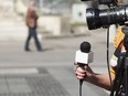 In this stock photo, a female news reporter holds a microphone during an interview.