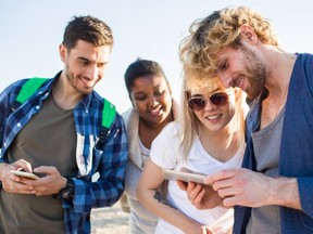 Friendly men and women with gadgets watching curious video on the beach