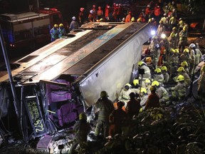 Firemen hurry to try to remove injured passengers from a double-decker bus lying on its side in Hong Kong, Saturday, Feb. 10, 2018.