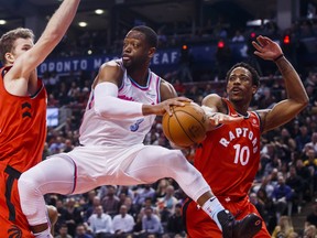 Miami Heat Dwyane Wade passes the ball off against Toronto Raptors Jakob Poeltl, left, and DeMar DeRozan during the second half of NBA basketball action in Toronto, Tuesday February 13, 2018. THE CANADIAN PRESS/Mark Blinch ORG XMIT: MDB22