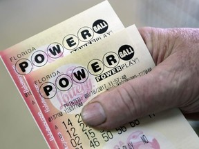 In this Aug. 18, 2017, file photo, a customer shows his purchased Powerball tickets in Hialeah, Fla.