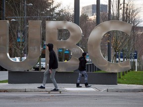 A man on a skateboard and a young woman pass large letters spelling out UBC at the University of British Columbia in Vancouver on Nov. 22, 2015.