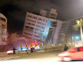 In this photo released by Hualien County Fire Bureau, rescuers are seen entering an building that collapsed onto its side from an early morning earthquake in Hualien County, eastern Taiwan, Wednesday, Feb. 7 2018.