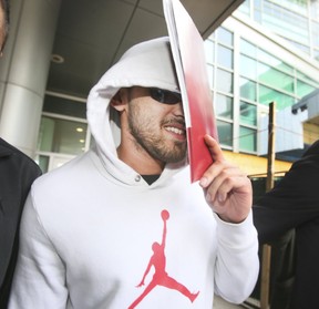 Parmvir Singh Chahil, 25, leaves Brampton court and runs into a construction wall while covering his face with a folder. (VERONICA HENRI, Toronto Sun)
