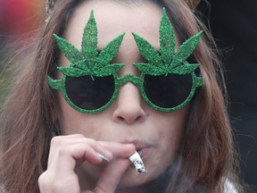 This file photo taken on April 20, 2017 shows a woman smoking marijuana on Parliament Hill waiting for the clock to hit 4:20pm on 4/20 in Ottawa. (GETTY IMAGES)