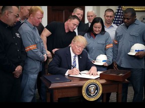 WASHINGTON, DC - MARCH 08:  Surrounded by steel and aluminum workers, U.S. President Donald Trump (C) signs a 'Section 232 Proclamation' on steel imports during a ceremony in Roosevelt Room the the White House March 8, 2018 in Washington, DC. Trump signed proclamations that will impose a 25-percent tarriff on imported steel and a 10-percent tarriff on imported alumninum.