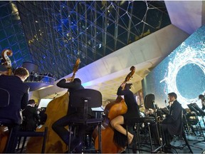 A symphony orchestra performs under the glass pyramide the Louvre museum during a private business event of the American global professional services company Accenture in Paris on September 20, 2016. Accenture Strategy has created a symphonic experience enabled by human insight and artificial intelligence technology.