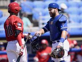 Jays catcher Russell Martin has his mask handed back to him in Saturday’s exhibition game by Canada junior T.J. Schofield-Sam. (AP Photo/Jason Behnken)