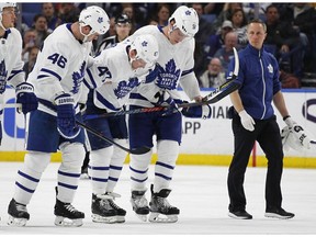 Toronto Maple Leafs forward Leo Komarov (47) is helped off the ice by Roman Polak (46) and Jake Gardiner (51) during the second period of an NHL hockey game against the Buffalo Sabres, Thursday, March 15, 2018, in Buffalo, N.Y.