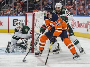 Connor McDavid of the Edmonton Oilers, looks for a play as he rounds the net beside Devan Dubnyk of the Minnesota Wild at Rogers Place in Edmonton on March 10, 2018.