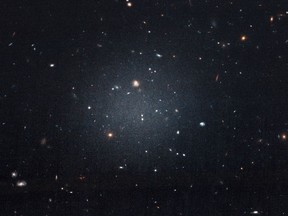 This Nov. 16, 2017 image made with the Hubble Space Telescope shows the diffuse galaxy NGC 1052-DF2, lighter area in centre. Several other galaxies can be seen through it. The unusual galaxy's stars are speeding around with no apparent influence from dark matter, according to a study published on Wednesday, March 28, 2018 in the journal Nature.