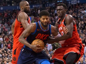 Oklahoma City Thunder Paul George drives between Toronto Raptors Pascal Siakam and Serge Ibaka during second half NBA basketball action in Toronto on March 18, 2018